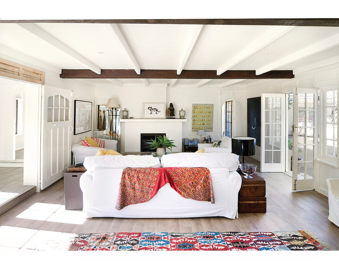 Living room with wooden floor, white walls, sofa set and terrace doors