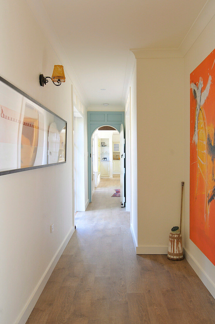 Long hallway with wooden floor and artworks on walls