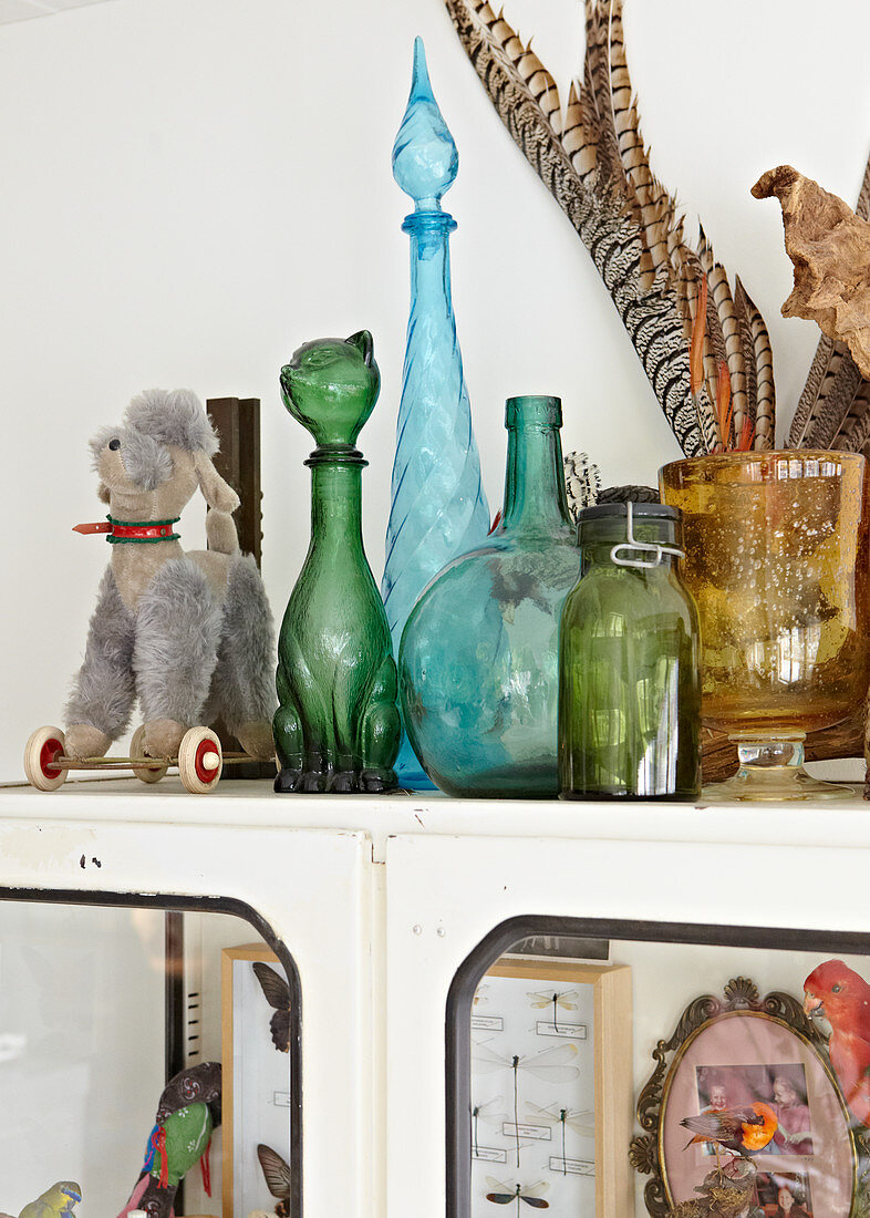 Verschiedene farbige Deko Flaschen und Spielzeug auf Vintage Schrank