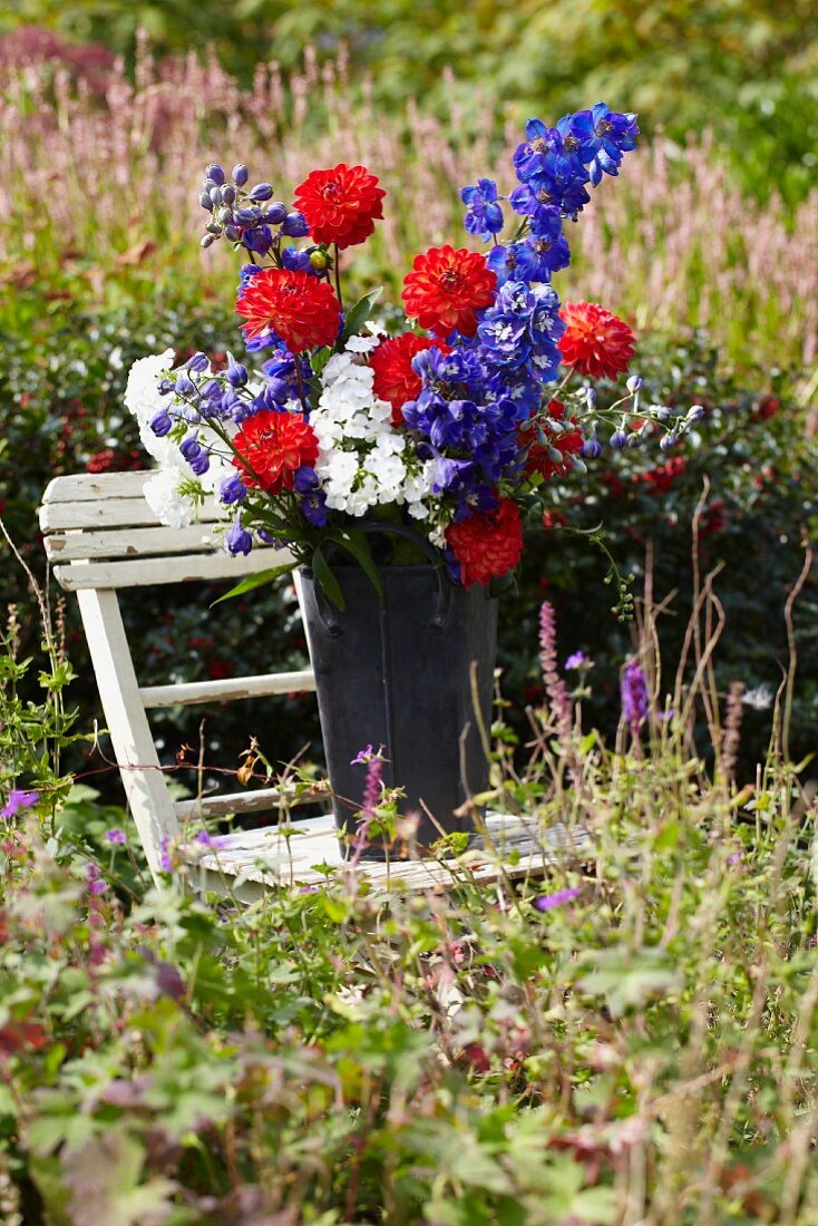 Sommerlicher Blumenstrauss im Zinkeimer auf Gartenstuhl