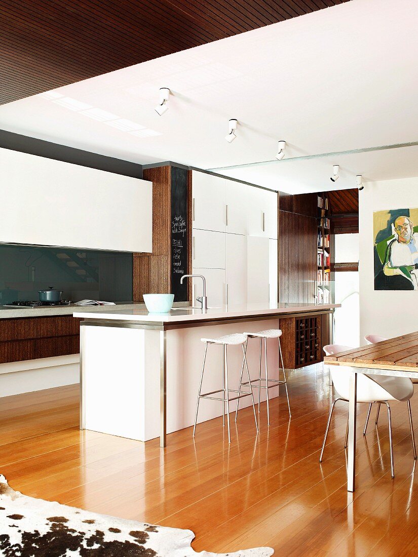 Moderne Küche mit weissen Fronten und Küchenblock mit Theke im offenen Wohnraum