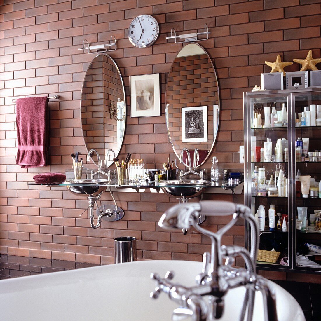 Badezimmer im Vintagestil - teilweise sichtbare Badewanne mit Vintage Armatur und moderner Waschtisch mit ovalen Spiegeln an Wand mit Ziegellook