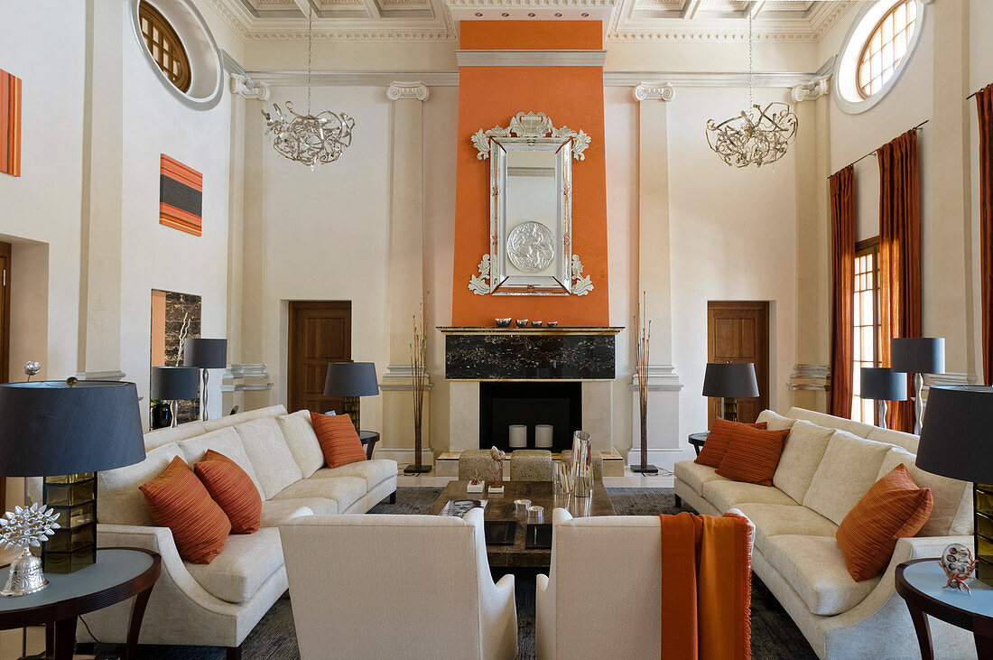 Grand salon with pale, classic upholstered furniture in front of open fireplace
