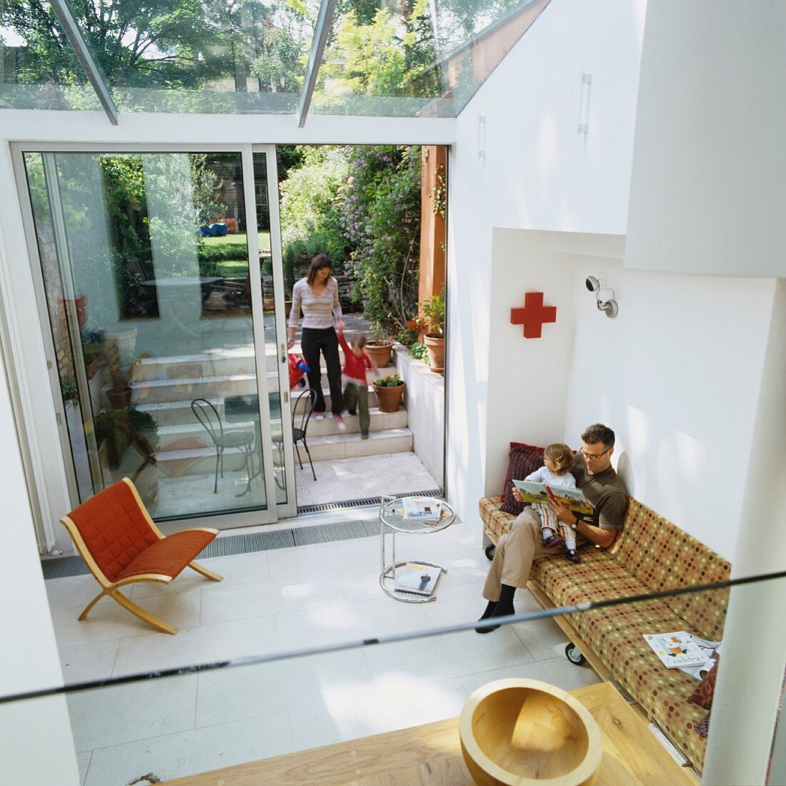 Familie in zeitgenössischem Wohnhaus - Blick von oben auf Couch und Klassiker Beistelltisch in minimalistischem Wohnzimmer mit Gartenzugang