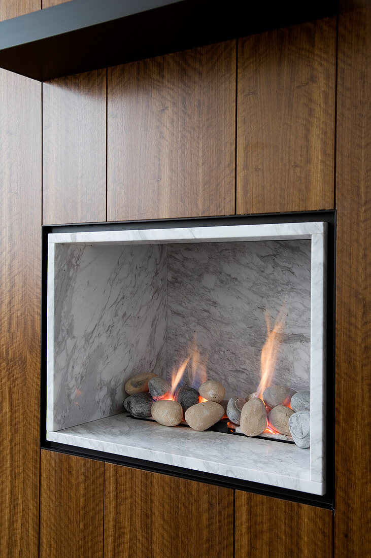 Gas fire with marble cladding and pebbles integrated into wooden wardrobe doors