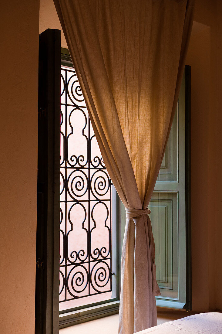 Gathered curtain in front of window with Moroccan-style grille
