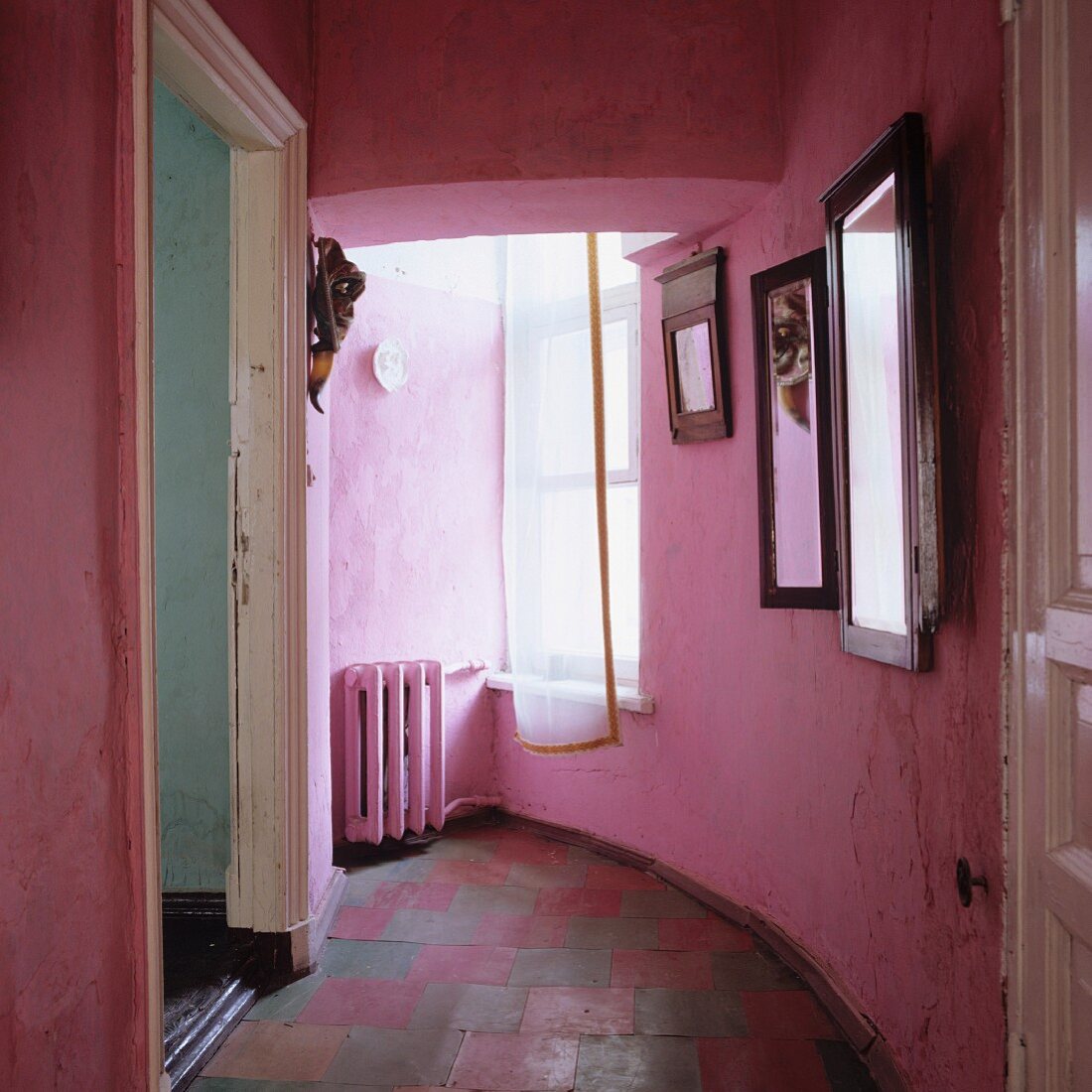 Pink, vintage corridor with curved wall and open door in period apartment