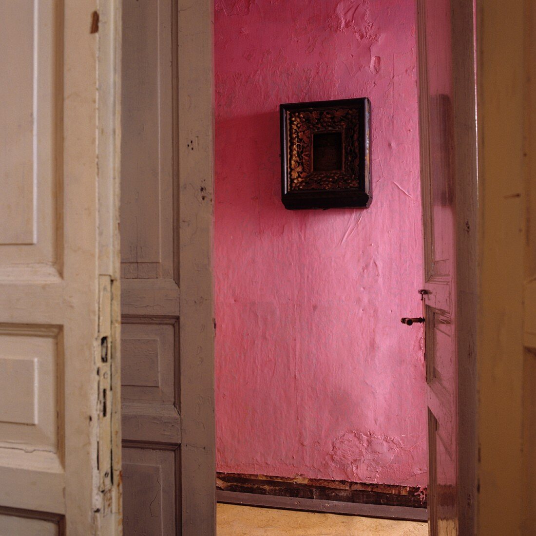 View through open door of picture on pink wall in corridor of period apartment