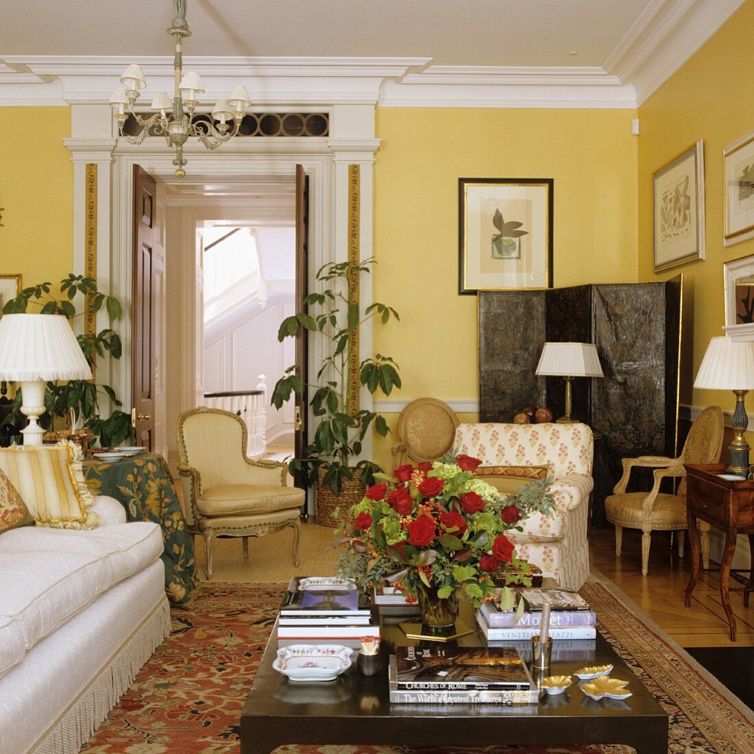Grand living in room in yellow with sofa and antique armchairs around coffee table