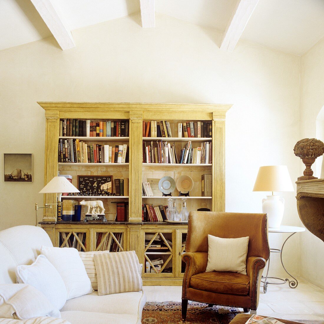 Bookcase, old leather armchair and sofa in living room of French country house