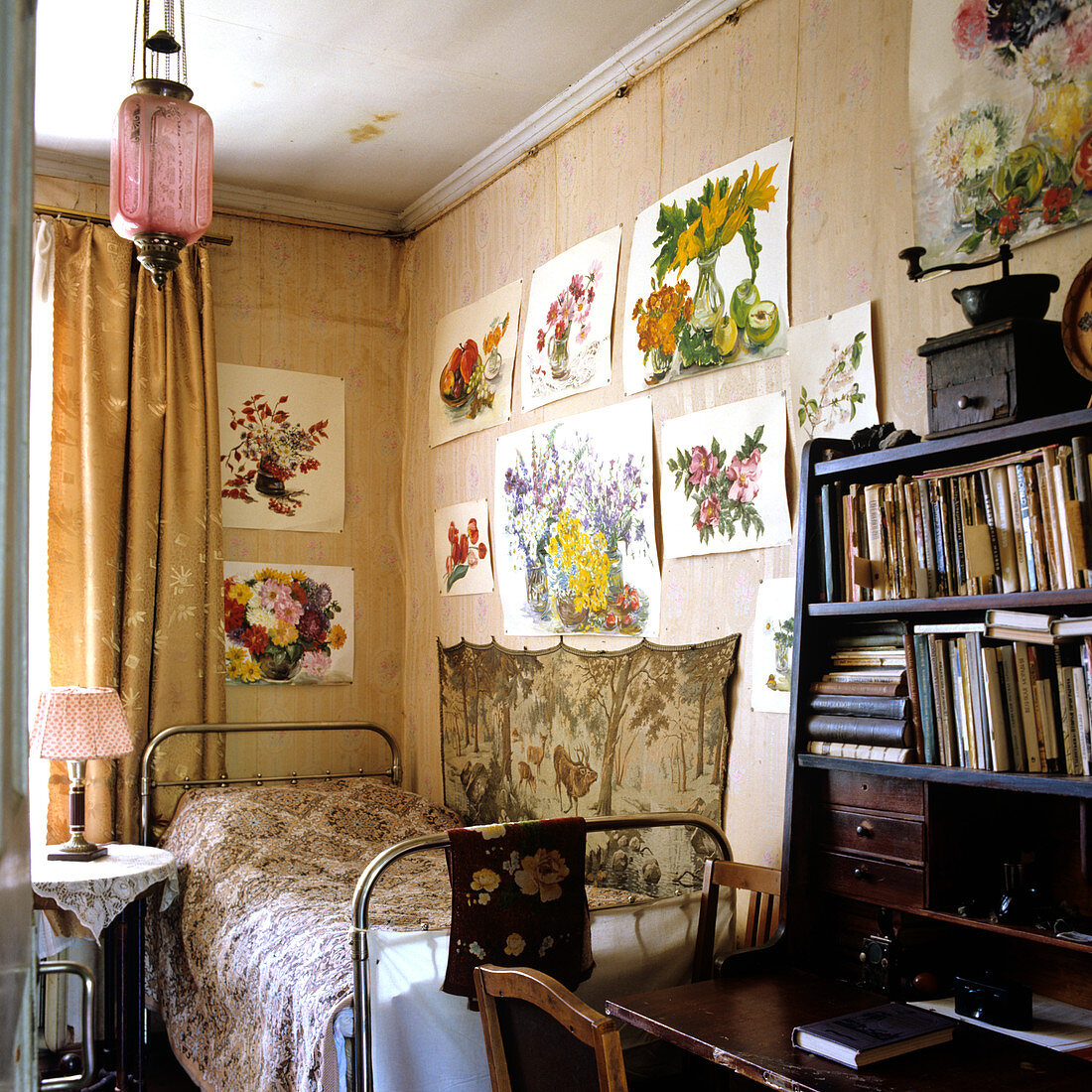 Zimmerecke mit schlichtem Bett und darüberhängenden, fröhlichen Blumenaquarellen
