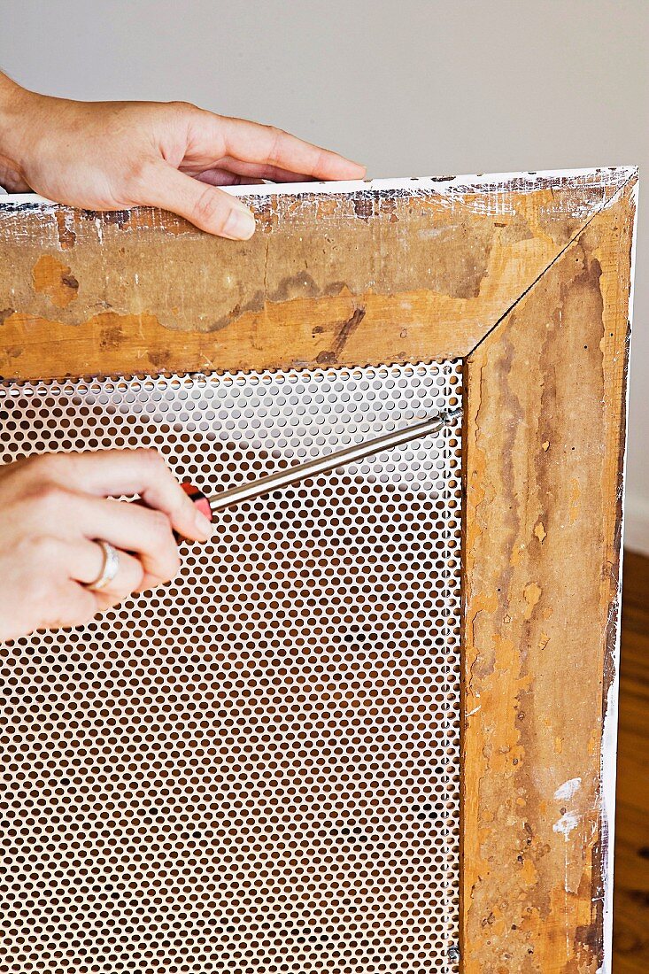 A wire mesh being fitted into a picture frame