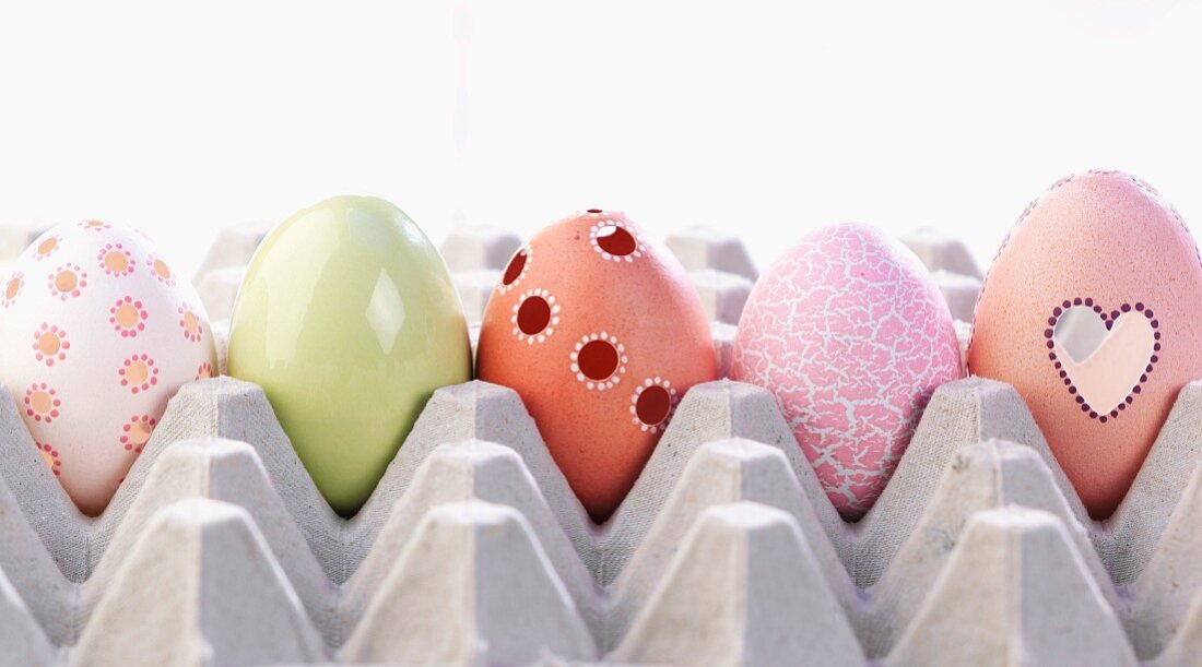 Fünf verschieden dekorierte Ostereier in Eierpalette