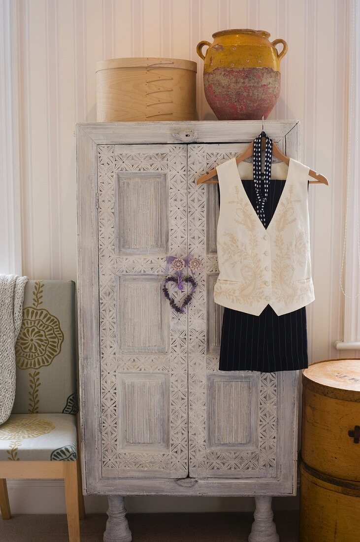 Weiß überstrichener Vintagekleiderschrank mit Schnitzereien im Schlafzimmer