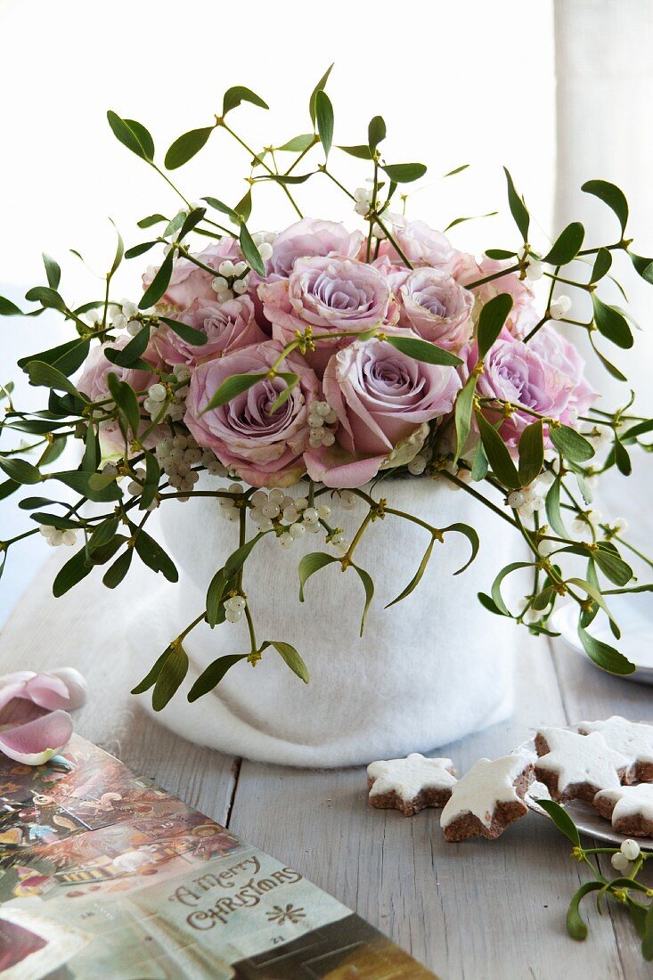 A bouquet if pink roses and mistletoe