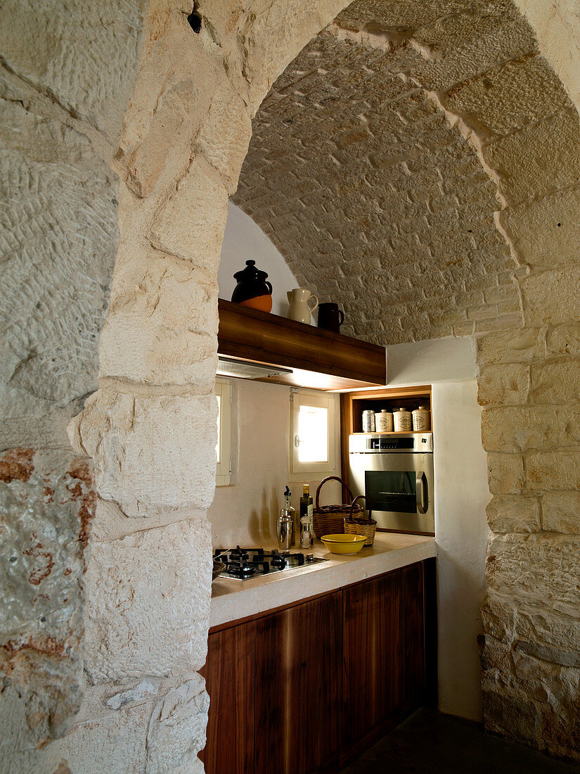 View through stone archway of simple kitchen counter in a Trullo house