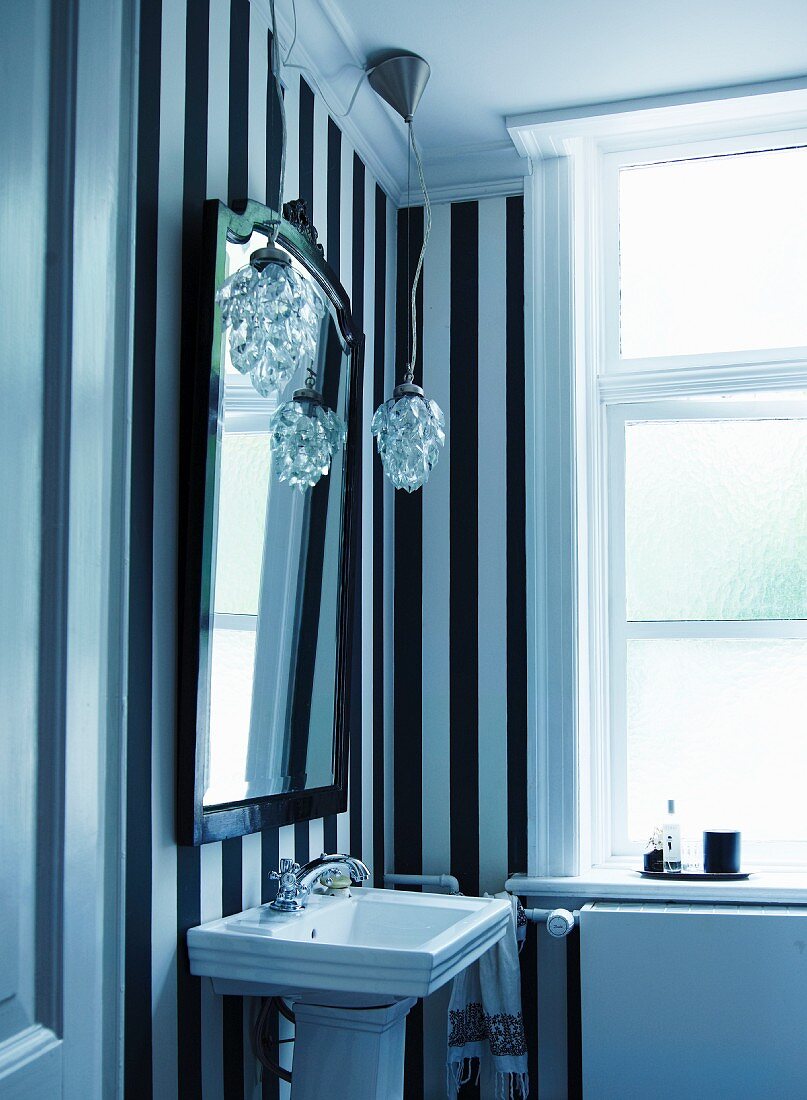 Washstand against black and white striped wall paper in vintage bathroom