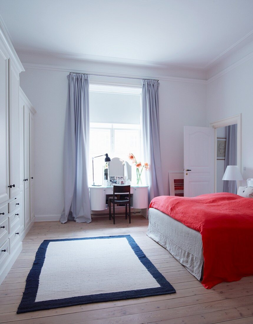 Red bedspread on bed in white bedroom