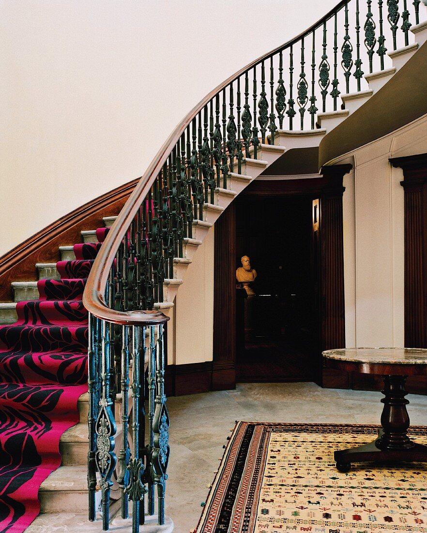 Curved staircase with modern runner in traditional foyer