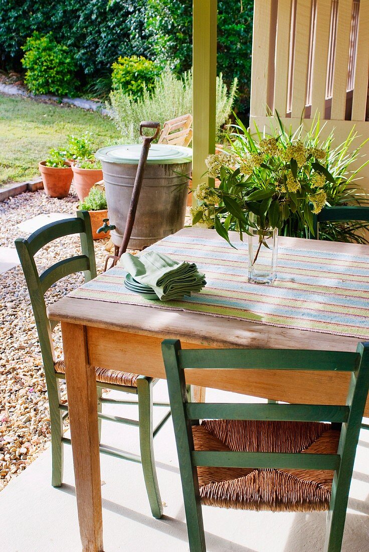 Rustic table and chairs on terrace with view of garden