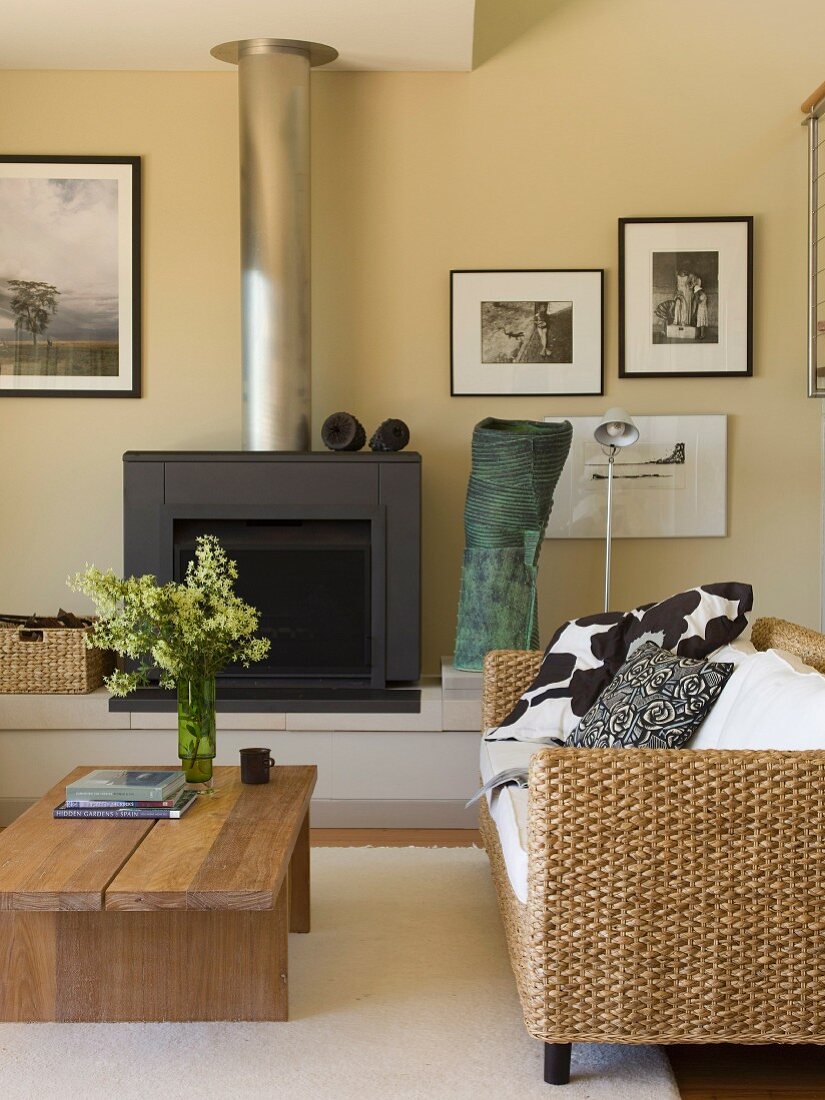 Sofa aus Rattan und rustikaler Couchtisch vor Kamin in modernem Wohnraum
