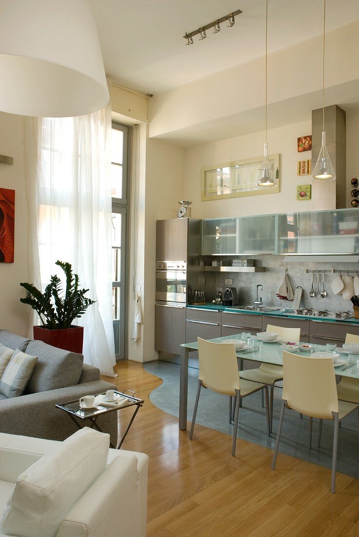 Open-plan interior with modern dining table and chairs in front of fitted kitchen