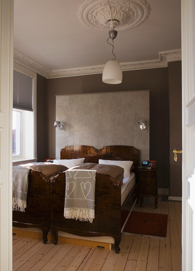 Antike Einzelbetten nebeneinander gestellt vor grau getönten Wänden mit Stuckfries