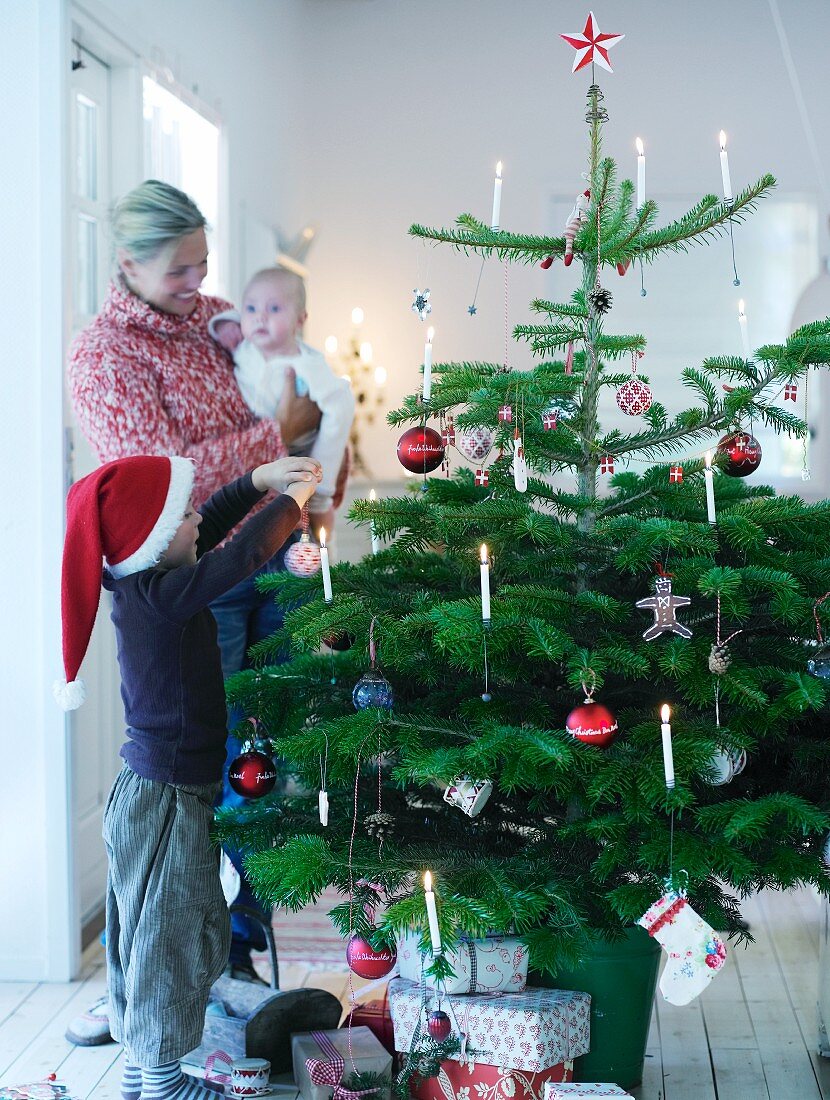 Familie mit Kind schmückt Weihnachtsbaum