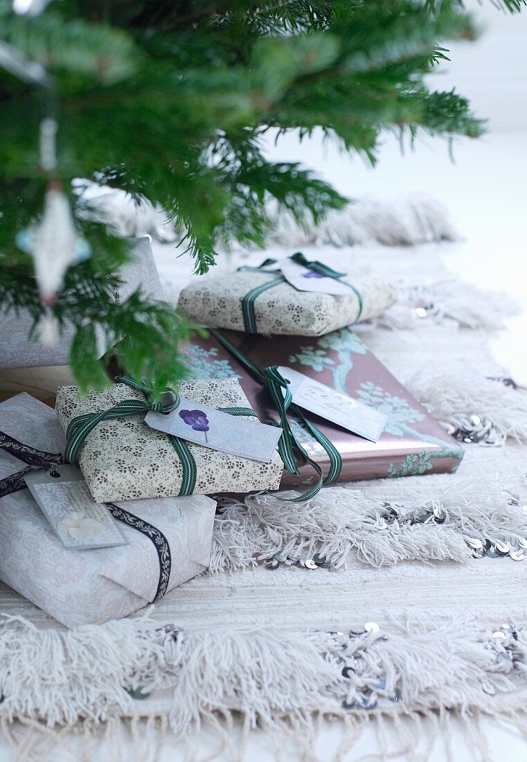 Verpackte Geschenke unter teilweise sichtbaren Weihnachtsbaum