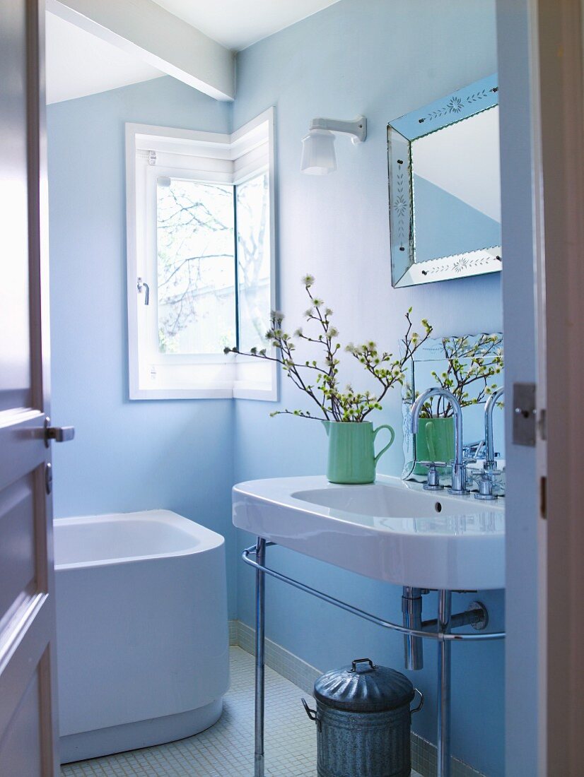 Blick durch offene Tür auf Waschtisch in hellblau getöntem Bad