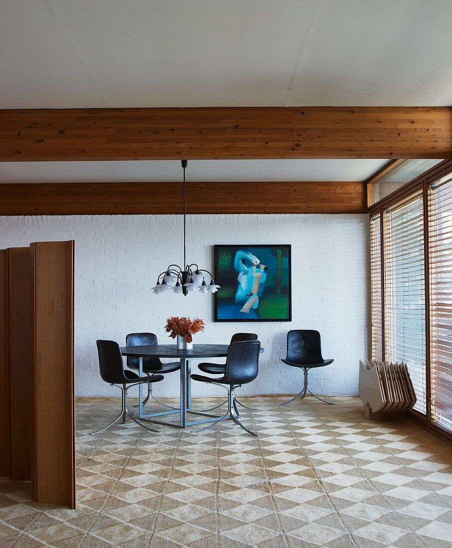 Essplatz mit schwarzen Schalenstühlen in minimalistischen Wohnraum mit Holzbalkendecke