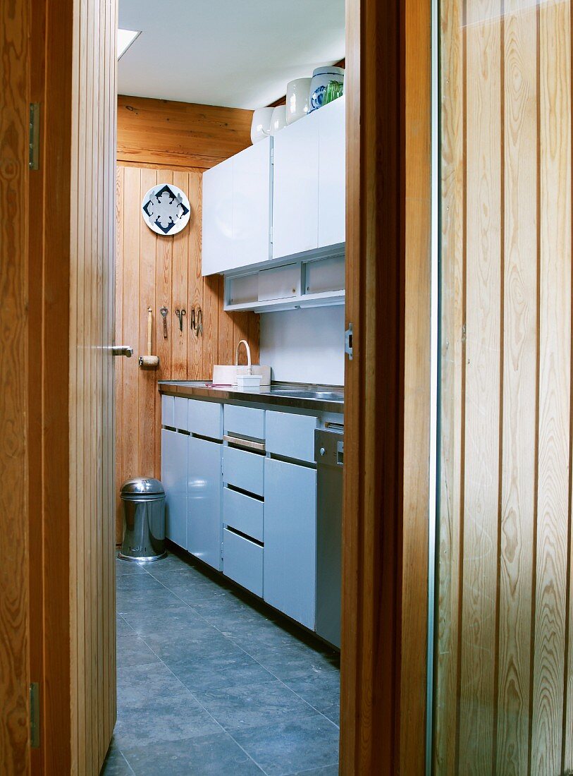 Blick durch offene Holztür in funktionale Küche