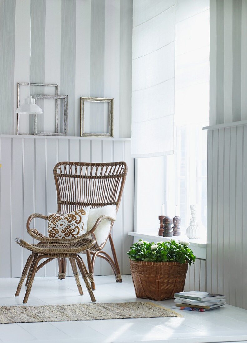 Basket chair in corner of bright room in front of white, half-height wood panelling