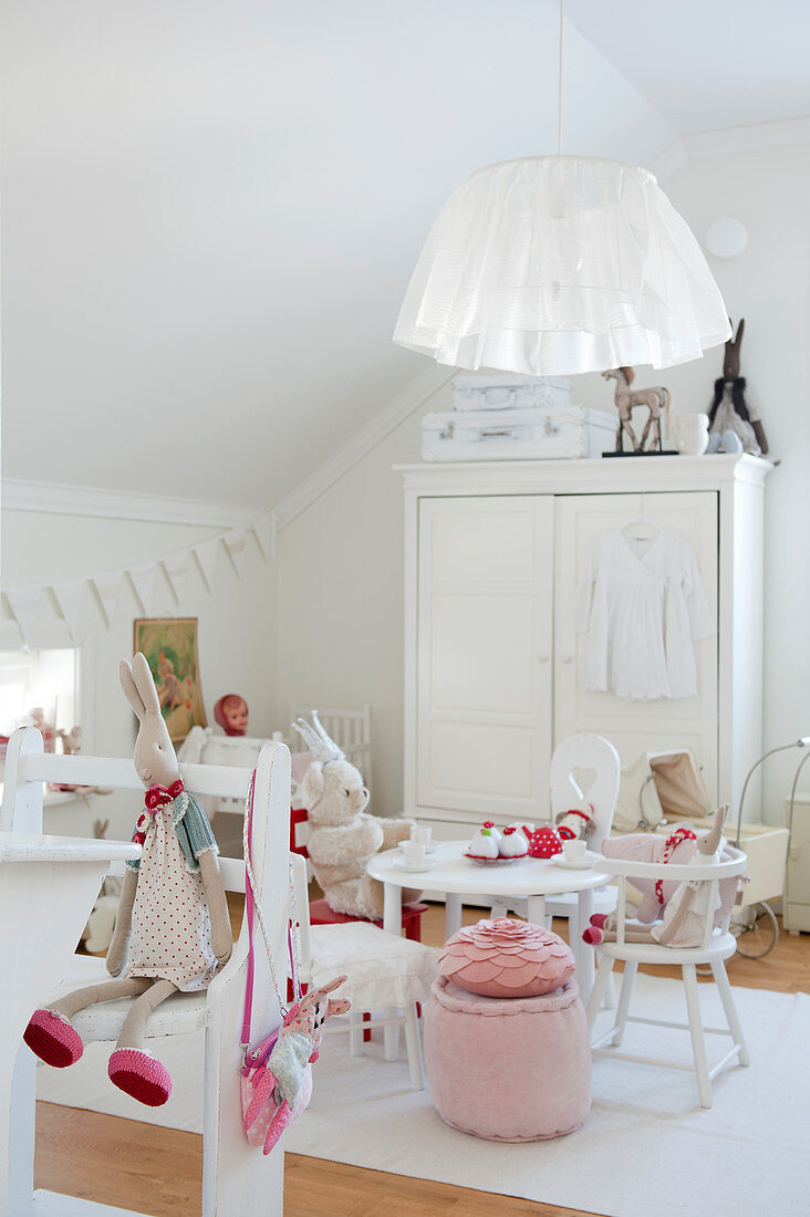 Kinderzimmer in skandinavischem Stil - weiße Stühle mit Stofftieren am Tisch vor weißem Kleiderschrank