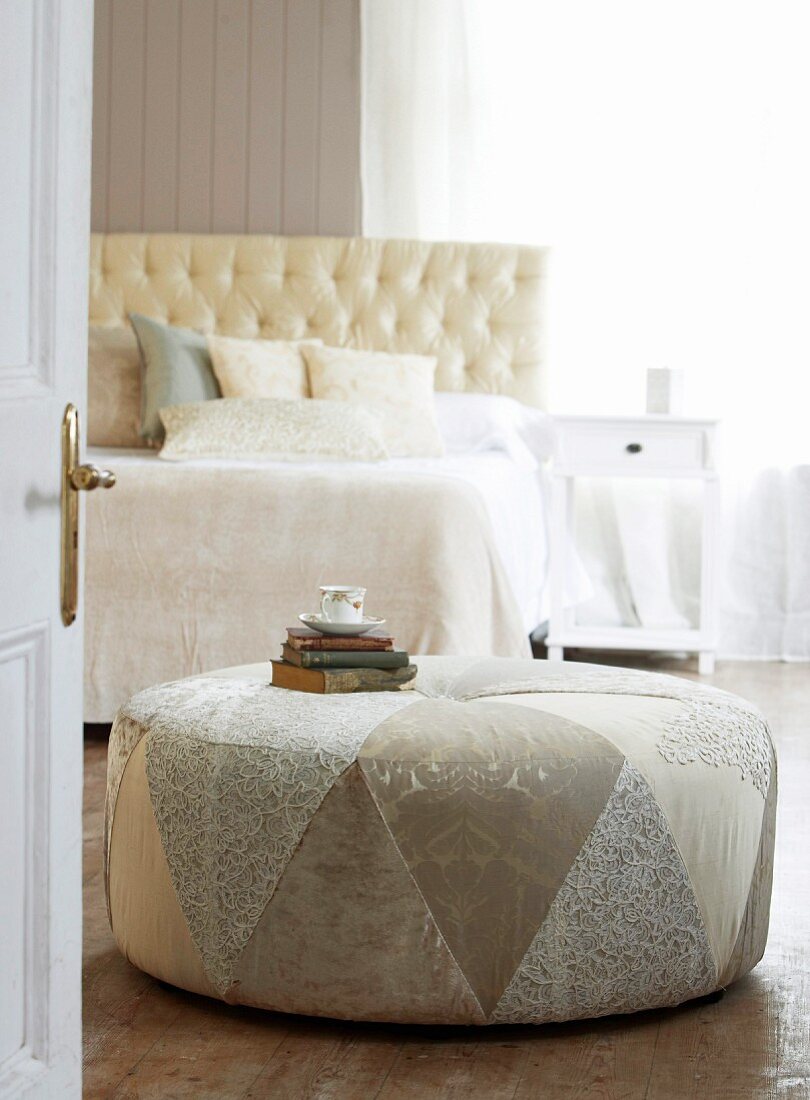View through an open door on an elegant upholstered furniture in a white bedroom