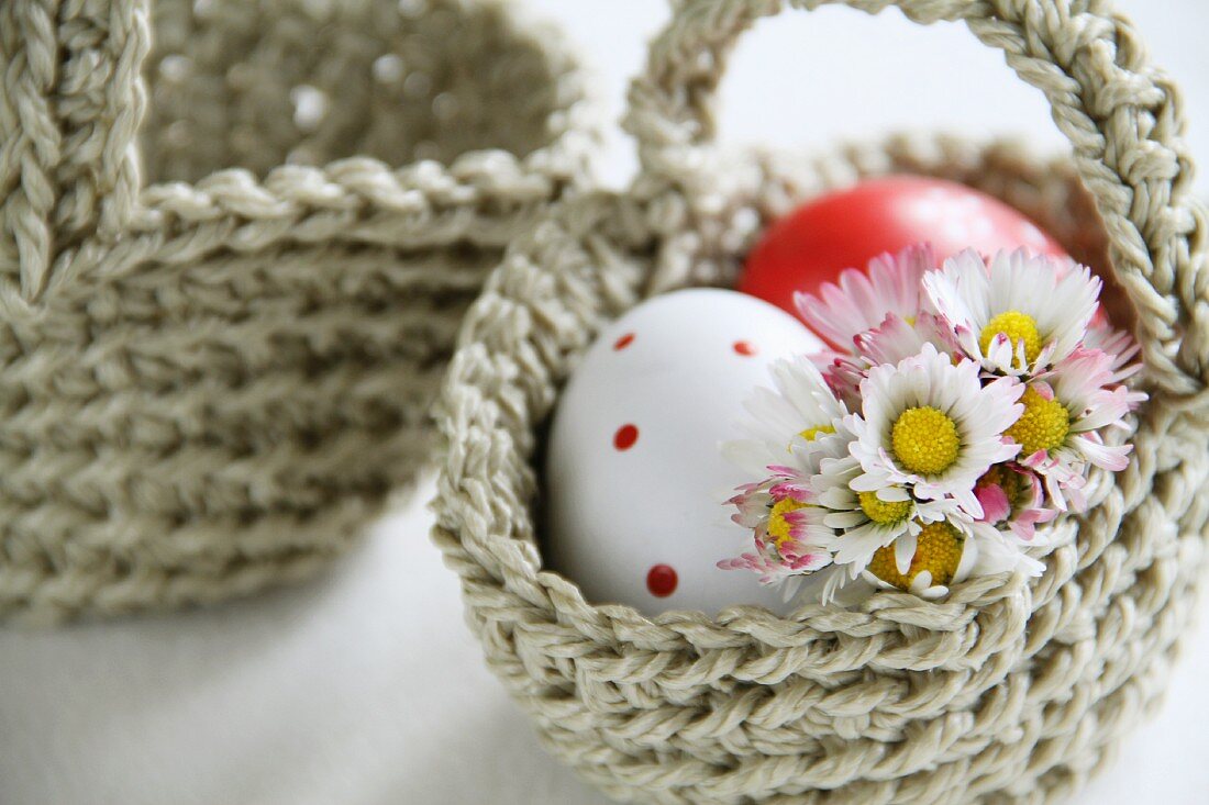 Gehäkeltes Körbchen mit Eiern und Gänseblümchen gefüllt