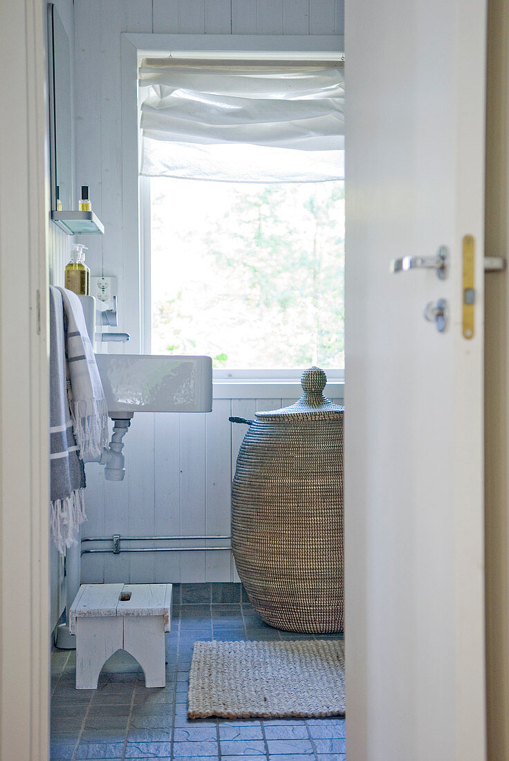 View through open door of rattan laundry basket in bathroom