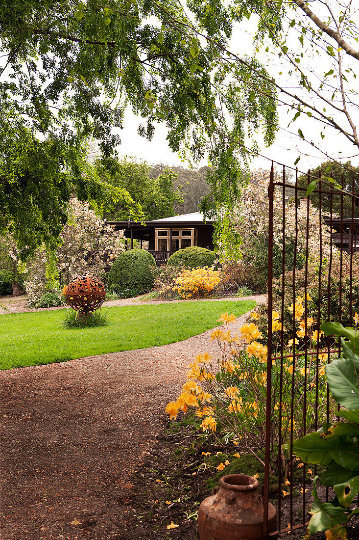 Blick durch offenes Gartentor in gepflegten Garten mit Wohnhaus