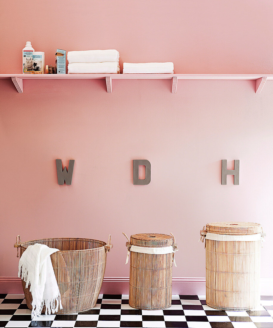 Badezimmer mit Selbstbau-Board an der roséfarbenen Wand und folkloristische Wäschekörbe auf kühlen Schachbrettfliesen