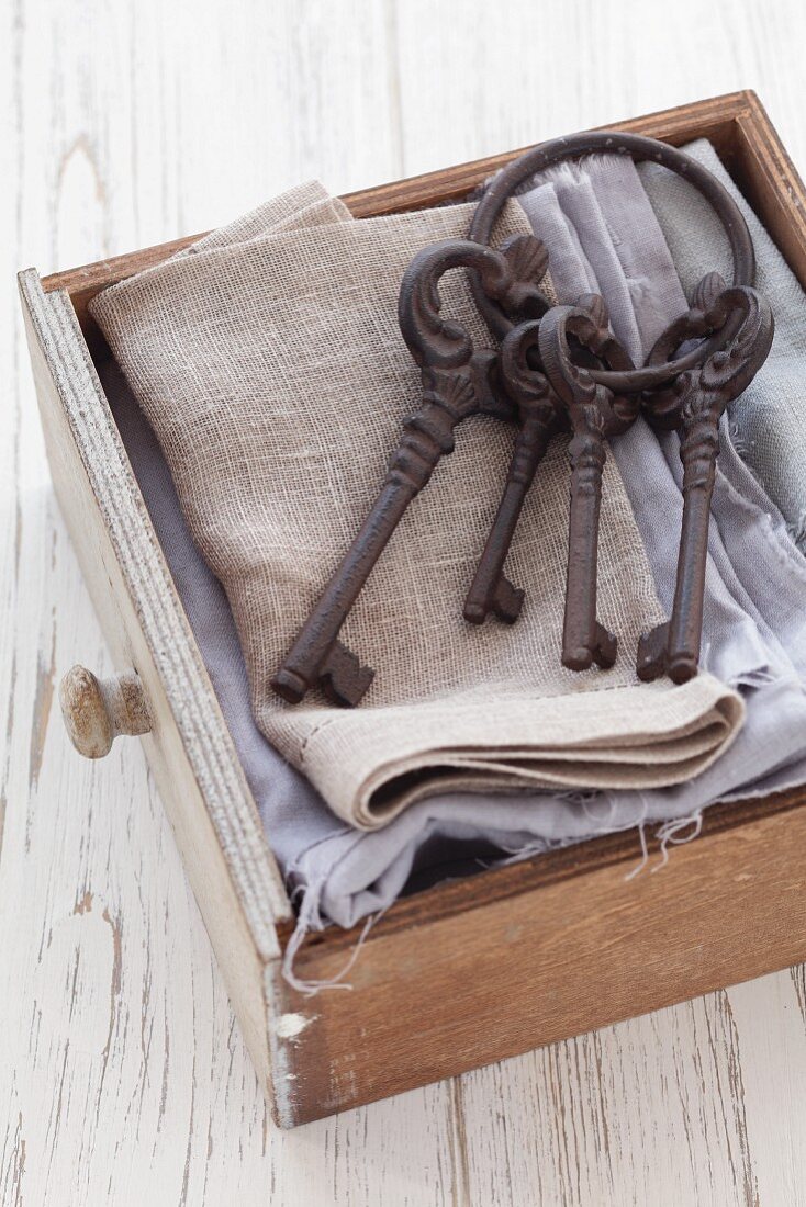 Schublade mit grauen Textilien und altem Schlüsselbund