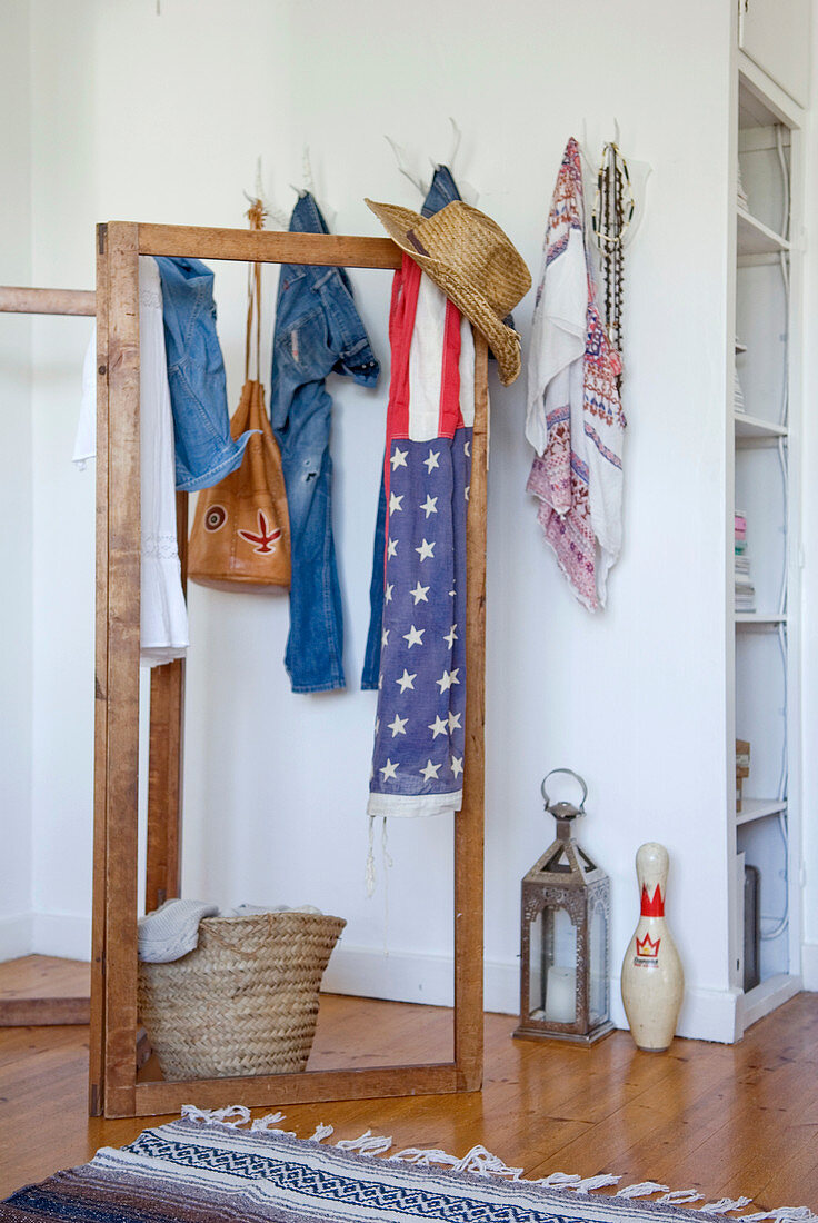 Holzparavent mit Strohhut und Schal mit amerikanischer Flagge vor Wand mit weißen Jagdtrophäen als Kleiderhaken genutzt