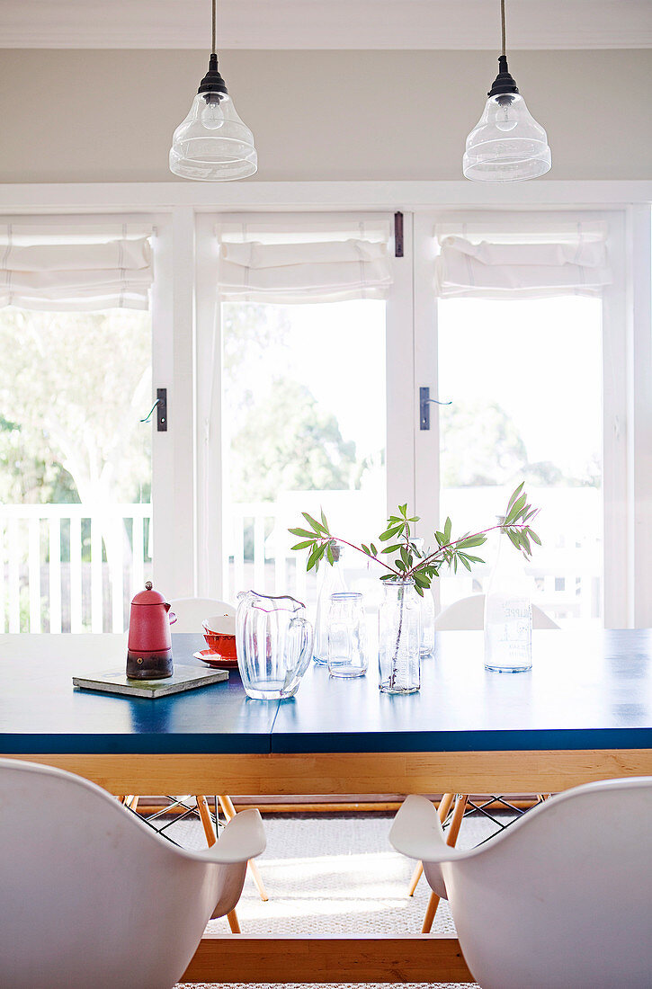 Dining table with blue top, white shell chairs and vintage glass pendant lamps