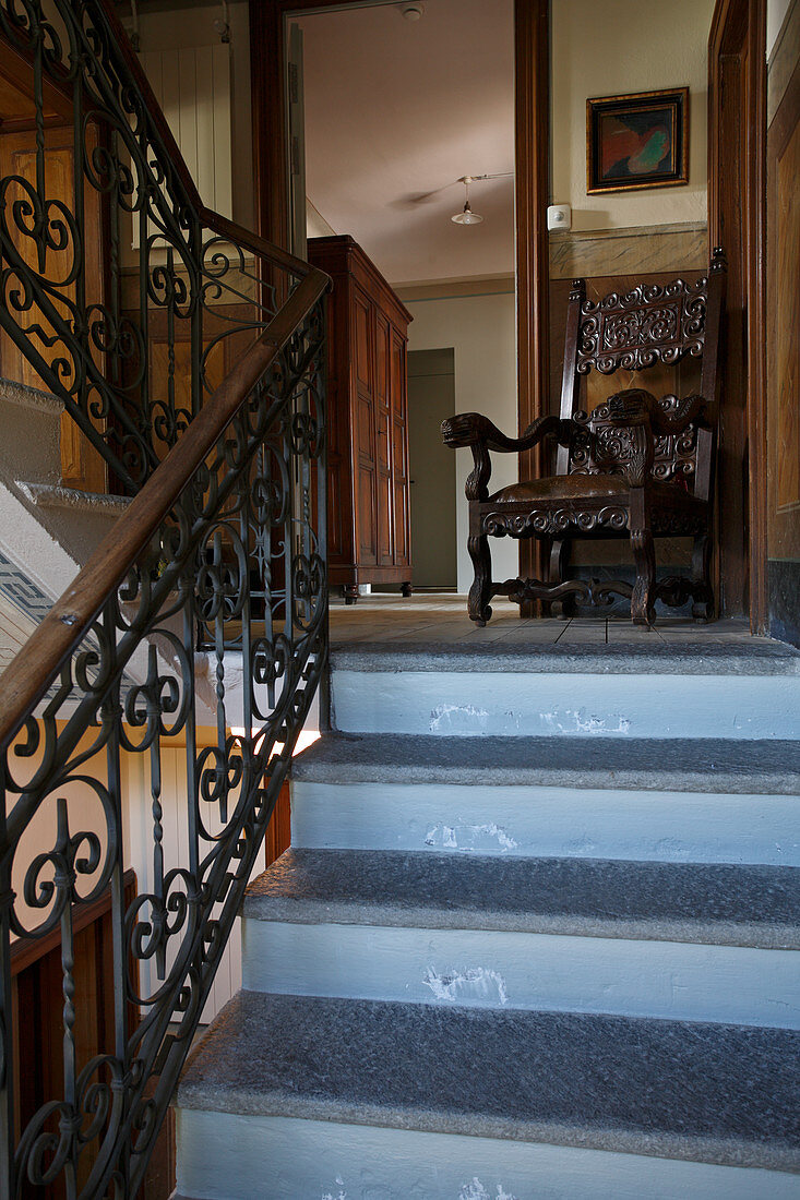 Treppenhaus einer Villa mit antikem Stuhl auf Treppenpodest