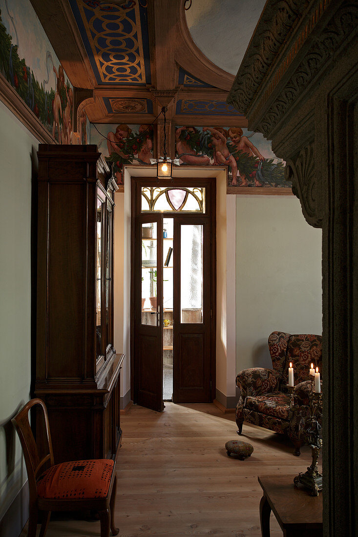 Herrschaftliche Wohnzimmerecke mit Vitrinenschrank und Sessel neben Zimmertür mit Oberlicht