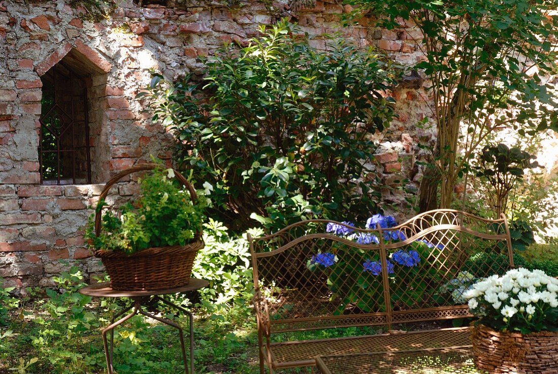 Verrostete Gartenbank und Gartentisch vor Backsteinmauer