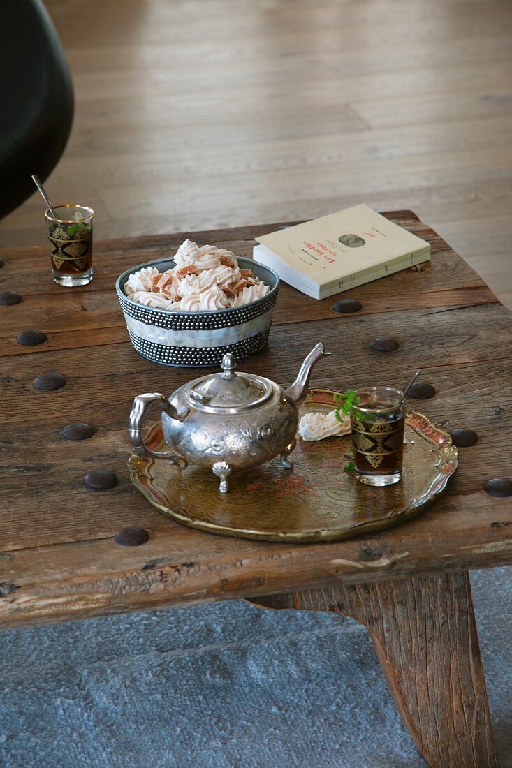 Tablett mit silberner Teekanne und Teeglas in orientalischem Stil auf rustikalem Holztisch