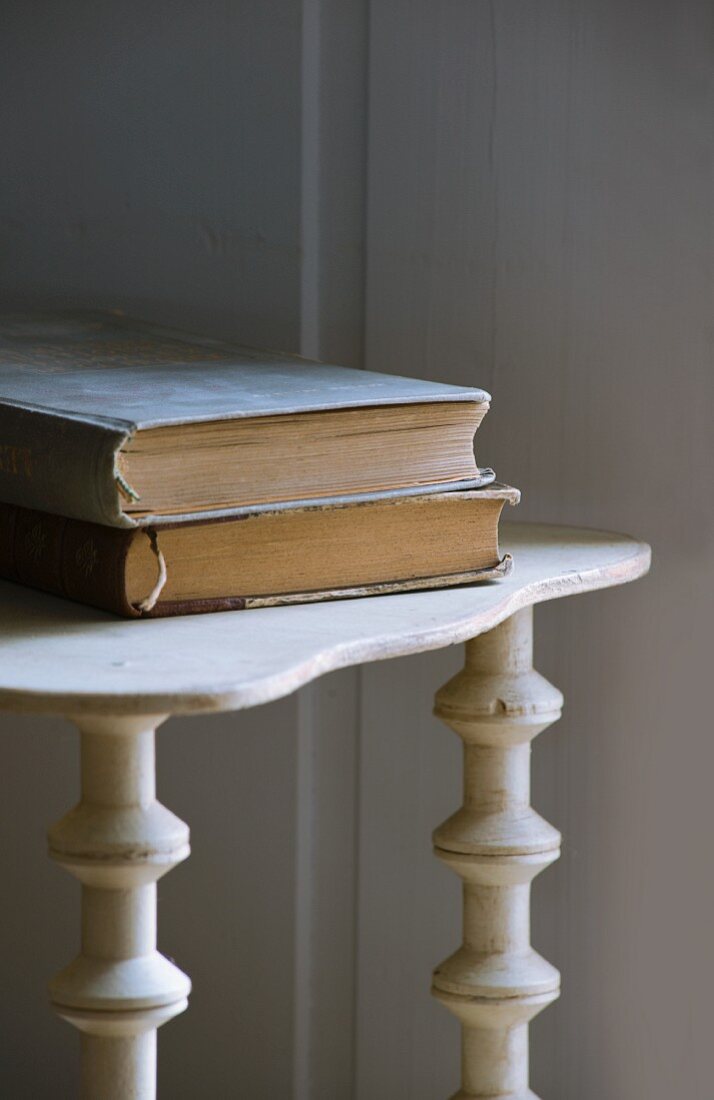 Zwei gebundene Bücher auf altem Holzregal mit Zierfüssen