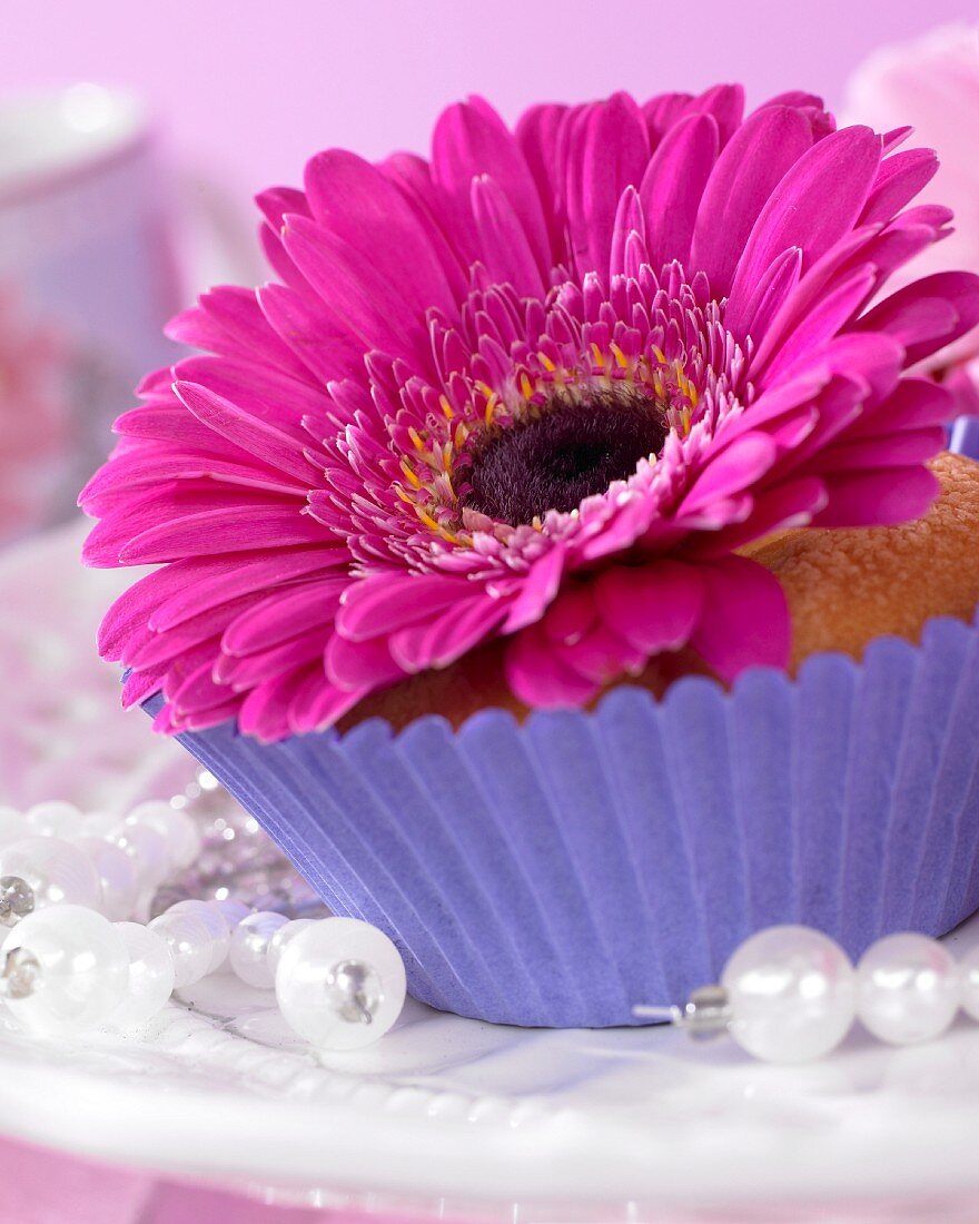 A muffin topped with a gerbera flower