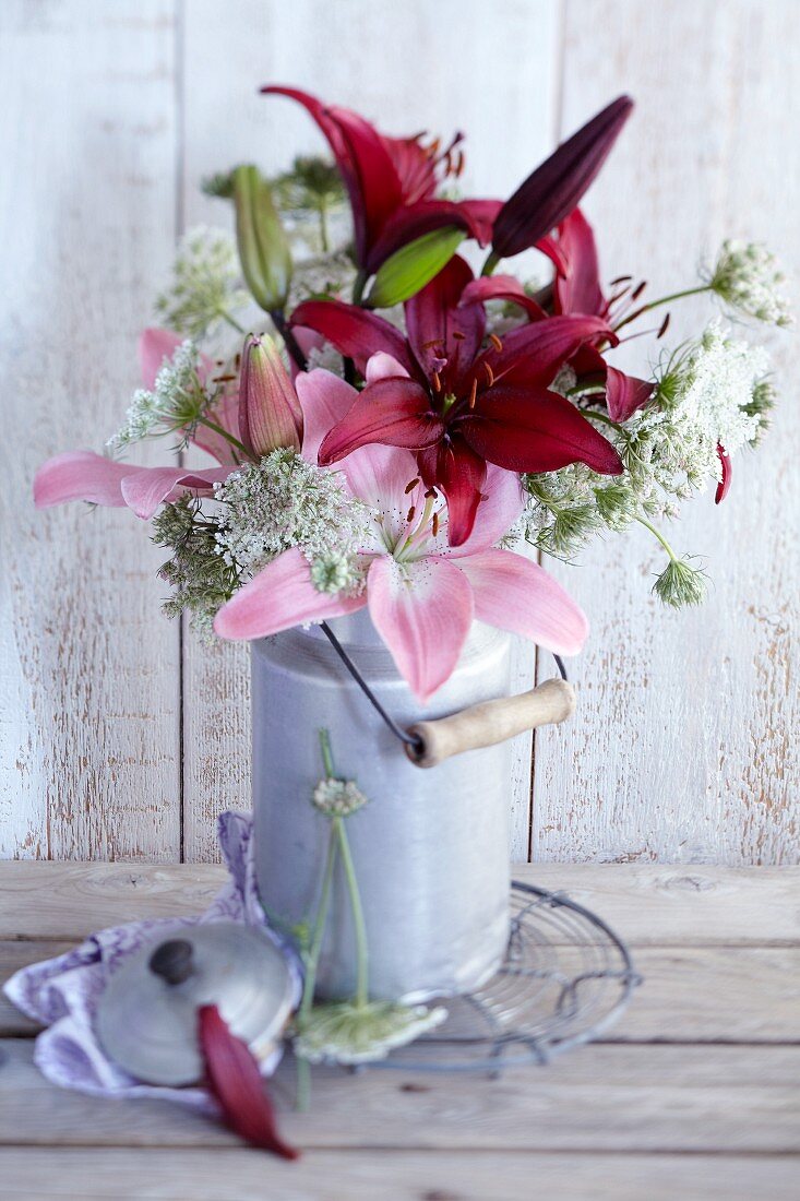 Bouquet of lilies and wild carrot in old milk can