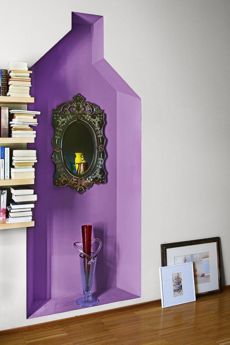 Aufgehängter Spiegel mit verziertem Rahmen und Bodenglasvase in violett getönter Wandnische